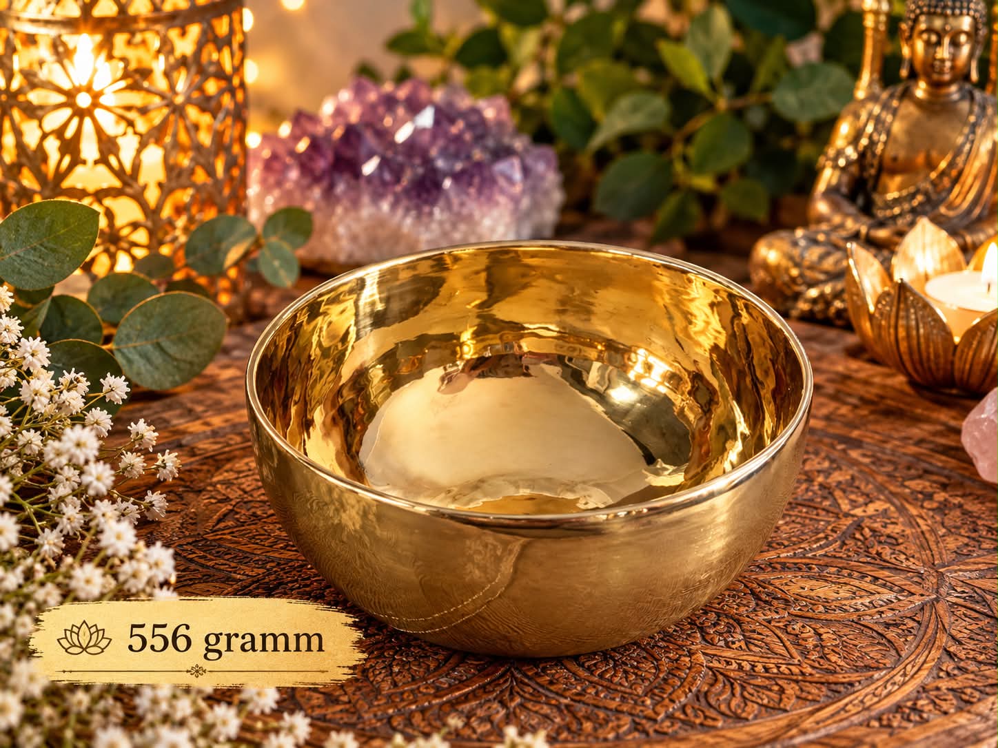 556 grammos, fényes aranyszínű tibeti hangtál, polírozott belső felülettel, faragott faalátéten, ametisztkristály és Buddha-szobor társaságában.